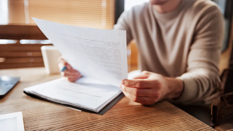 Una persona leyendo un formulario en papel sobre una mesa