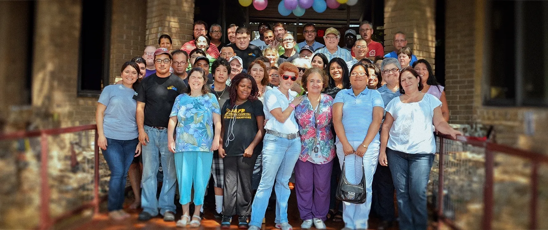 Un grupo grande de miembros y personal de Clubhouse posando juntos frente a un edificio de ladrillo