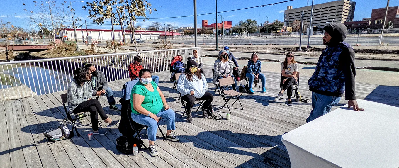 Miembros del Clubhouse sentados en círculo en una terraza al aire libre