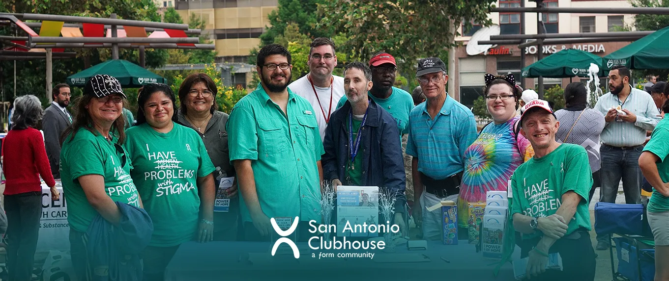Miembros y personal de San Antonio Clubhouse con camisetas verdes iguales, reunidos al aire libre bajo los árboles