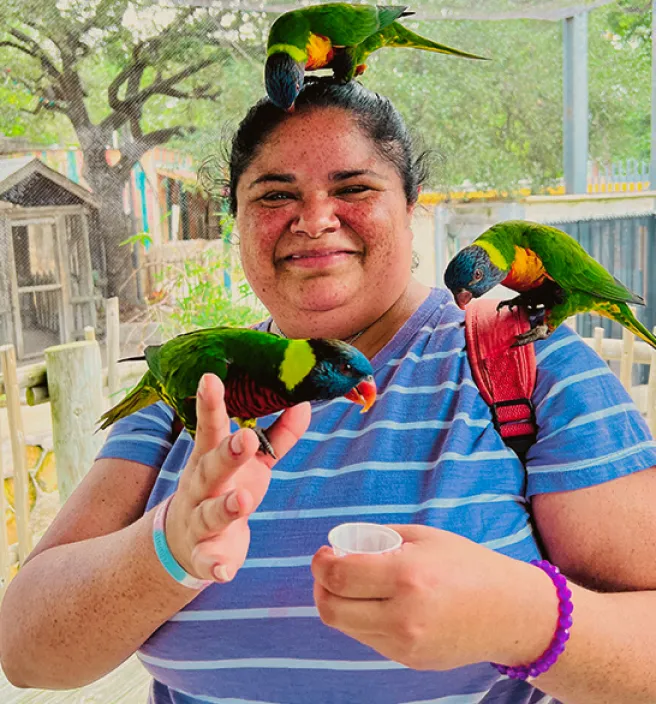 Una miembro de Clubhouse sonriendo con dos pericos de colores