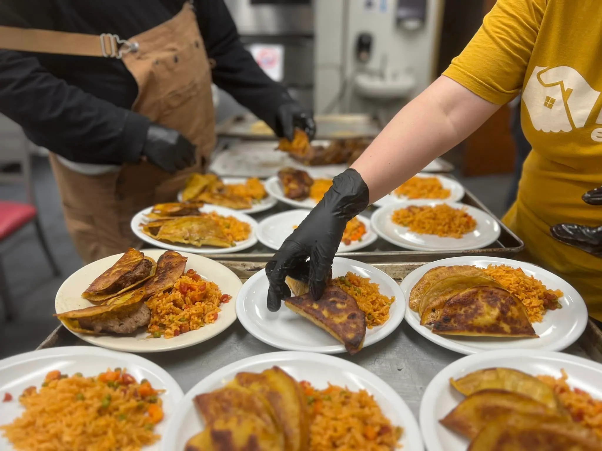 Gloved hands plating tacos and rice for lunch in the Wellness Cafe